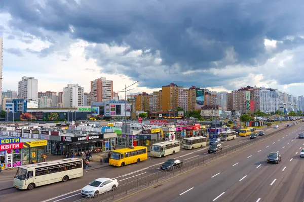 Kyiv, Ukrayna - 19 Mayıs 2025: Ukrayna 'nın başkenti Kyiv' de bulutlu bir gökyüzü altında trafik, mağazalar ve yüksek binalarla Prospekt Bazhana 'da hareketli bir caddenin geniş açılı görüntüsü.
