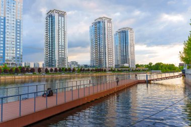 Kyiv, Ukrayna - 19 Mayıs 2025: Kyiv 'deki Riverstone konut kompleksi, günbatımında nehir kenarındaki modern mimariyi su üzerindeki yansımalarla sergiledi..