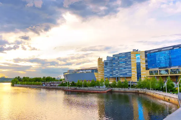 Kyiv, Ukrayna - 19 Mayıs 2025: Günbatımında Kyiv 'deki River Mall yakınlarındaki rıhtımda gezinen ve modern mimari ve doğal güzellikleri gözler önüne seren insanların canlı sahnesi.