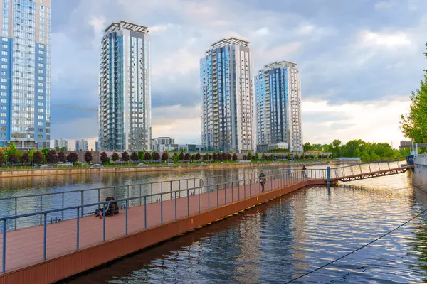 Kyiv, Ukrayna - 19 Mayıs 2025: Kyiv 'deki Riverstone konut kompleksi, günbatımında nehir kenarındaki modern mimariyi su üzerindeki yansımalarla sergiledi..