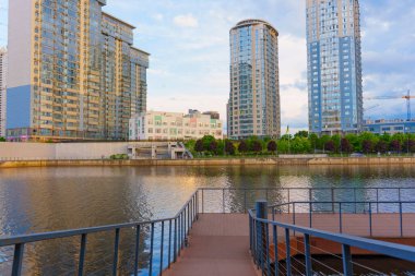 Kyiv, Ukrayna - 19 Mayıs 2025: Dnipro Nehri 'ndeki bir rıhtımdan görülen Riverstone konut kompleksinin manzarası, çağdaş mimari ve sakin bir su yüzeyi sergilenmektedir..