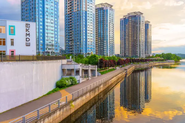 Kyiv, Ukrayna - 19 Mayıs 2025: Dinyeper Nehri boyunca çağdaş binaların manzarası, Ukrayna 'nın başkenti Kyiv' de gün batımında suyun üzerindeki yansımalarını gösteriyor.