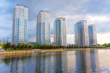 Kyiv, Ukrayna - 19 Mayıs 2025 Kyiv 'deki Riverstone konut kompleksinin manzarası, bulutlu bir akşamda nehir boyunca uzanan yüksek binaları vurguluyor..