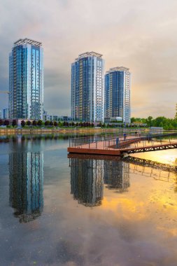 Kyiv, Ukrayna - 19 Mayıs 2025: Ukrayna 'nın başkenti Kyiv' deki bir nehrin suyuna yansıyan, gün batımında Riverstone yerleşim merkezinin geniş açılı görüntüsü.