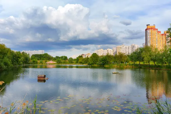 Kyiv, Ukrayna - 19 Mayıs 2025: Poznyaky Gölü manzaralı sakin sular ve dramatik bulutlar sergilenen Kyiv 'deki konut binaları ve yeşillik manzaralı.