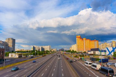 Kyiv, Ukrayna - 19 Mayıs 2025: Kyiv 'deki Poznyaky bölgesinin geniş açılı görüntüsü, çarpıcı bir gökyüzü altında trafik ve şehirler arası otobüslerin yoğun olduğu bir yol gösteriyor.