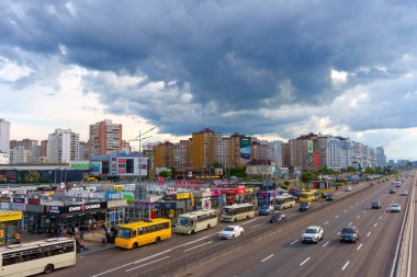 Kyiv, Ukrayna - 19 Mayıs 2025: Kyiv 'deki Poznyaky metro istasyonunun geniş açılı görüntüsü, otobüsleri, trafiği ve kasvetli gökyüzü altındaki binaları gösteriyor.