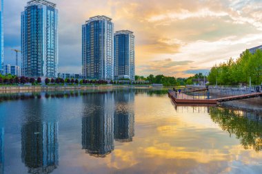 Kyiv, Ukrayna - 19 Mayıs 2025: Günbatımında Ukrayna 'nın başkenti Kyiv' de günbatımında suda yansıyan Riverstone konut kompleksinin modern mimari ve huzur dolu atmosferini gösteren görüntüsü.