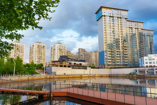 Kyiv, Ukrayna - 19 Mayıs 2025: Kyiv 'deki River Mall yakınlarındaki modern yerleşim alanlarının geniş açılı görüntüsü, yemyeşil ve günbatımında yansıtıcı su kütlesi.