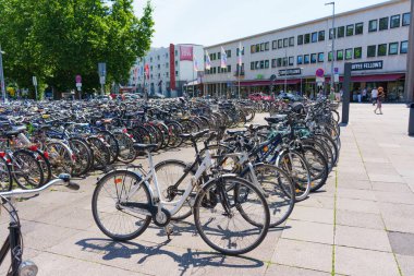 Heidelberg, Almanya - 21 Haziran 2025: Parlak güneş ışığı altında kalabalık bir şehir merkezinde parketmiş çok sayıda bisikletin geniş açılı görüntüsü.