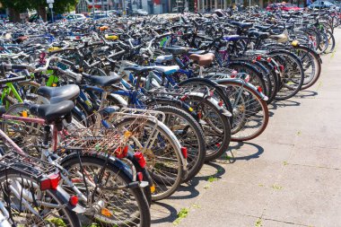Heidelberg, Almanya - 21 Haziran 2025: Parlak güneş ışığı altında çeşitli stil ve renkleri gösteren yoğun bir sıra bisiklet kentsel bir ortamda park edilmiş.