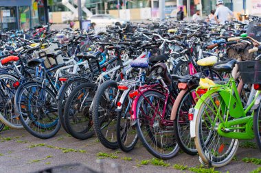Heidelberg, Almanya - 21 Haziran 2025: Gündüz vakti yakalanan çok sayıda farklı renk ve stilde bisikletin bulunduğu kalabalık park alanı.