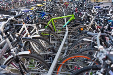 Heidelberg, Almanya - 21 Haziran 2025: Yoğun bir bisiklet parkındaki siyah bisikletlerle çelişen canlı yeşil bir bisikletin yakın görüntüsü.