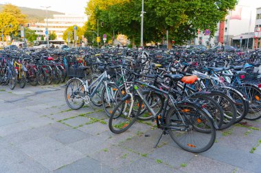 Heidelberg, Almanya - 21 Haziran 2025: Geniş park alanı yoğun bisiklet nüfusu ile dolu, akşam ışığı sırasında çeşitli stiller ve renkler sergileniyor.