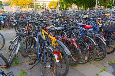 Heidelberg, Almanya - 21 Haziran 2025: Gündüz saatlerinde kentsel alanda sayısız farklı renk bisikletinin yer aldığı yoğun bir bisiklet parkı.