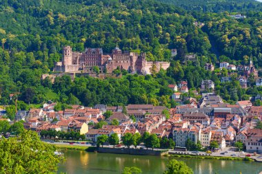 Heidelberg, Almanya - 21 Haziran 2025: Heidelberg Şatosu 'nun, Neckar Nehri' nin ve ön plandaki renkli binaların hava manzarası, parlak gün ışığında ele geçirildi.