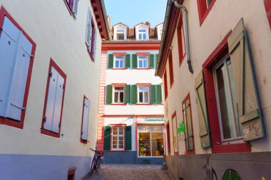 Heidelberg, Almanya - 21 Haziran 2025: Heidelberg 'de dar bir sokak, renkli panjurlar, klasik mimari ürünler ve yakınlarda parkedilmiş, güpegündüz yakalanmış bir bisiklet..