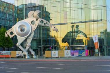 Heidelberg, Almanya - 21 Haziran 2025: Yansıtıcı cam bir binanın önünde tuhaf bir figürün büyük metalik heykeli.