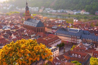 Heidelberg 'in eski kasabasının ikonik binaları ve yumuşak sabah ışığıyla aydınlanan Neckar Nehri' nin havadan görünüşü..
