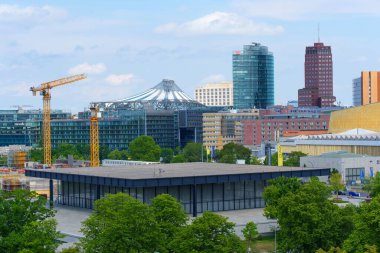 Berlin, Almanya - 31 Mayıs 2025: Berlin 'deki Yeni Ulusal Galeri' nin geniş açılı görüşü, arka planda Potsdamer Platz silueti ve inşaat vinçleri ile modern mimarisini sergiliyor.