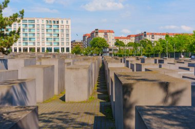Berlin, Almanya - 31 Mayıs 2025: Gri beton döşemeler, kentsel arka plan, açık gökyüzü ve yeşil ağaçlarla Avrupa 'da öldürülen Yahudilerin anısına yapılan anıt.