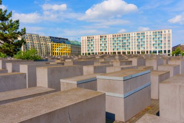 Berlin, Almanya - 31 Mayıs 2025: Öldürülen Avrupa Yahudilerinin anısına, beton levhalar kasvetli bir atmosfer yaratıyor, Berlin 'deki modern mimariyle yan yana, parlak mavi bir gökyüzü altında..