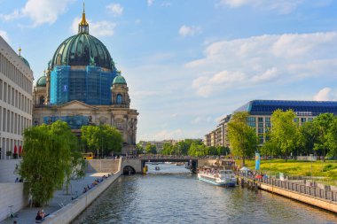 Berlin, Almanya - 31 Mayıs 2025: Spree Nehri 'nin yanında Berlin Katedrali, arka planda Redisson Oteli ve kıyıları saran yemyeşil ağaçlar yer alıyor..