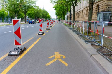 Berlin, Almanya - 1 Haziran 2025: Berlin 'deki kentsel inşaat sahnesinde işaretli yaya yolu, uyarı bariyerleri ve şehir yolu boyunca açık tabela yer alıyor.