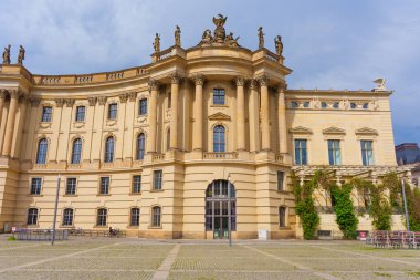 Berlin, Almanya - 1 Haziran 2025: Berlin 'deki Humboldt Üniversitesi' nin klasik mimari, heykeller ve kolonların yer aldığı ana binası bulutlu bir gökyüzüne karşı kurulmuştur..
