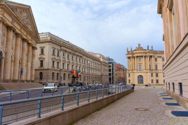 Berlin, Almanya - 1 Haziran 2025: Berlin 'deki tarihi binaların mimari ayrıntılar, araçlar ve tepesinde bulutlu bir gökyüzü bulunan bisikletlerle sokak manzarası.