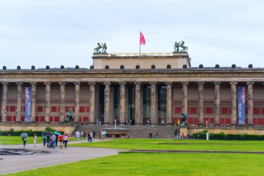 Berlin, Almanya - 1 Haziran 2025: Klasik mimari, heykeller ve Berlin, Almanya 'da ziyaretçilerin yer aldığı Eski Müze cephesinde canlı afişler ve bulutlu bir gökyüzü sergilenmektedir..