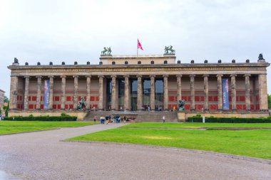 Berlin, Almanya - 1 Haziran 2025: Berlin 'deki tarihi Altes Müzesi cephesinde bulutlu bir gökyüzünde klasik mimari, büyük sütunlar ve canlı pankartlar yer alıyor..