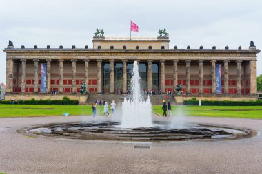 Berlin, Almanya - 1 Haziran 2025: Berlin 'deki Altes Müzesi' nin merkezi bir çeşme, klasik mimari ve ziyaretçilerin yer aldığı ön görünümü, bulutlu bir atmosferde ele geçirildi.