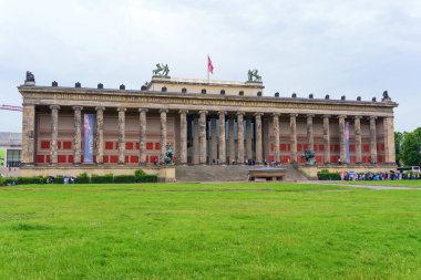 Berlin, Almanya - 1 Haziran 2025: Berlin 'deki Altes Müzesi' nin büyük sütunlarını, klasik mimarisini ve bulutlu bir gökyüzü altında yemyeşil çevreleri vurguluyor..