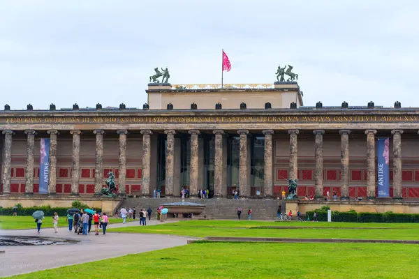 Berlin, Almanya - 1 Haziran 2025: Klasik mimari, heykeller ve Berlin, Almanya 'da ziyaretçilerin yer aldığı Eski Müze cephesinde canlı afişler ve bulutlu bir gökyüzü sergilenmektedir..