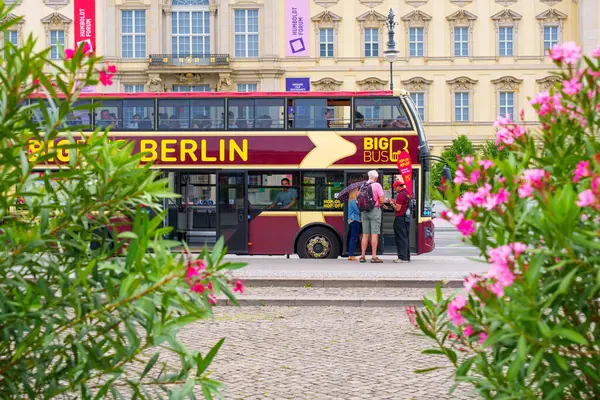 Berlin, Almanya - 1 Haziran 2025: Humboldt Forum yakınlarına park etmiş renkli çift katlı otobüs, canlı çiçekler ve Berlin 'deki turistlerle çevrili.
