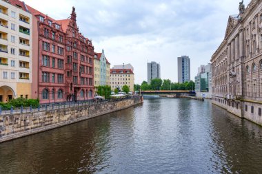 Berlin, Almanya - 1 Haziran 2025: Nikolaiviertel 'deki Spree Nehri' nin kıyılarını kaplayan tarihi mimarinin görüntüsü, Berlin 'de geleneksel ve modern binaların bir karışımını sergiliyor.