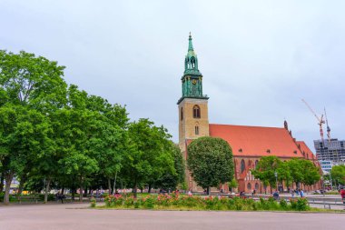 Berlin, Almanya - 1 Haziran 2025: Berlin 'deki canlı ağaçlar ve bahçelere yerleşmiş Aziz Mary Kilisesi' nin panoramik manzarası, farklı kulesini ve mimari özelliklerini gözler önüne seriyor..