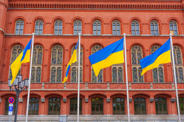 Берлин, Германия - 1 июня 2025 года: Разноцветные украинские флаги, размахивающие ветром против исторической Красной ратуши, с яркой архитектурой из красного кирпича и большими витражами.