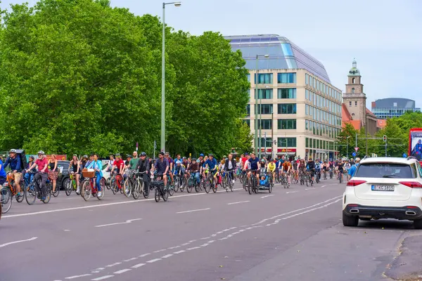 Berlin, Almanya - 1 Haziran 2025: Kentsel binalar ve yeşilliklerle çevrili geniş bir şehir yolunda bisiklet süren bir kalabalık, Berlin 'de hareketli ve aktif bir günü yakalıyor..