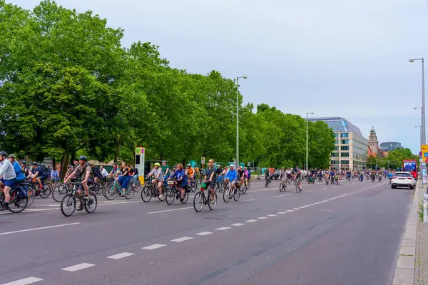Berlin, Almanya - 1 Haziran 2025 Berlin 'de geniş bir cadde boyunca, yemyeşil ağaçlar ve modern mimariyle çevrili, dinamik bir şehir atmosferi yaratan sayısız bisikletçinin canlı sahnesi.