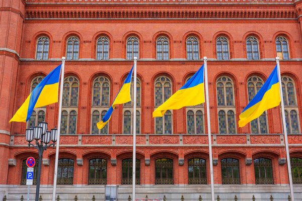 Берлин, Германия - 1 июня 2025 года: Разноцветные украинские флаги, развевающиеся на ветру против яркого фасада знаменитой красной ратуши Берлина, запечатлели момент культурного самовыражения.