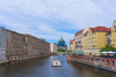 Berlin, Almanya - 1 Haziran 2025: Spree Nehri üzerinde yükselen Berlin Katedrali manzarası, tarihi binalar kıyıları kaplıyor ve parlak mavi bir gökyüzü canlı bir atmosfer yaratıyor.