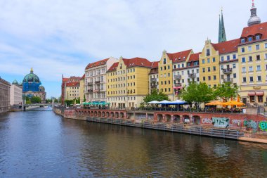 Berlin, Almanya - 1 Haziran 2025: Spree Nehri 'nin yanındaki Berlin Katedrali' nin canlı görüntüsü, tarihi binalar ve canlı renklerin yer aldığı, mimari ve kentsel yaşamın bir karışımını yakaladığı.
