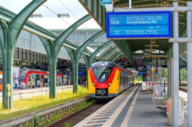 Darmstadt, Almanya - 16 Haziran 2025: Darmstadt Hauptbahnhof istasyonuna gelen renkli bölgesel tren modern mimari ve hareketli platform faaliyetlerini sergiliyor.
