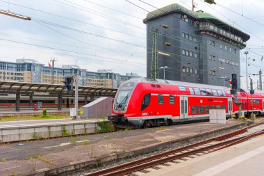 Frankfurt, Almanya - 10 Haziran 2025: Dinamik kentsel mimari ve demiryolu altyapısının yer aldığı Frankfurt Hauptbahnhof 'a park edilmiş modern kırmızı çift katlı trenin yakın görüntüsü.
