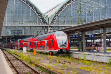 Frankfurt, Almanya - 10 Haziran 2025: Frankfurt 'ta konuşlanmış kırmızı bölgesel tren, cam tavan altında modern mimari ve demiryolu altyapısını gözler önüne seriyor.