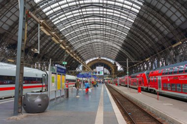 Frankfurt, Almanya - 10 Haziran 2025: Frankfurt 'ta modern trenler ve yüksek kemerli tavanın yer aldığı yoğun bir tren istasyonunun iç görünümü.