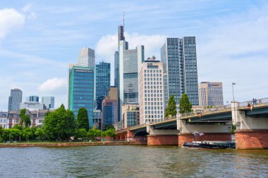 Frankfurt, Almanya - 10 Haziran 2025: Frankfurt 'un yüksek gökdelenleri, bir köprü ve şehrin canlı kentsel manzarasını gösteren ana nehrin panoramik manzarası.