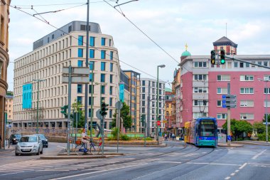 Frankfurt, Almanya - 10 Haziran 2025: Frankfurt 'ta modern binaların, tramvayın ve bulutlu bir gökyüzü altında trafik işaretlerinin yer aldığı bir kavşakta canlı şehir manzarası.